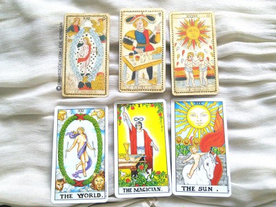 Comparaison entre le Tarot de Marseille (en haut) et Tarot Rider Waite (en bas) - Arcanes Majeurs Le Monde, Le Bateleur (Le Magicien pour Rider Waite) et le Soleil.